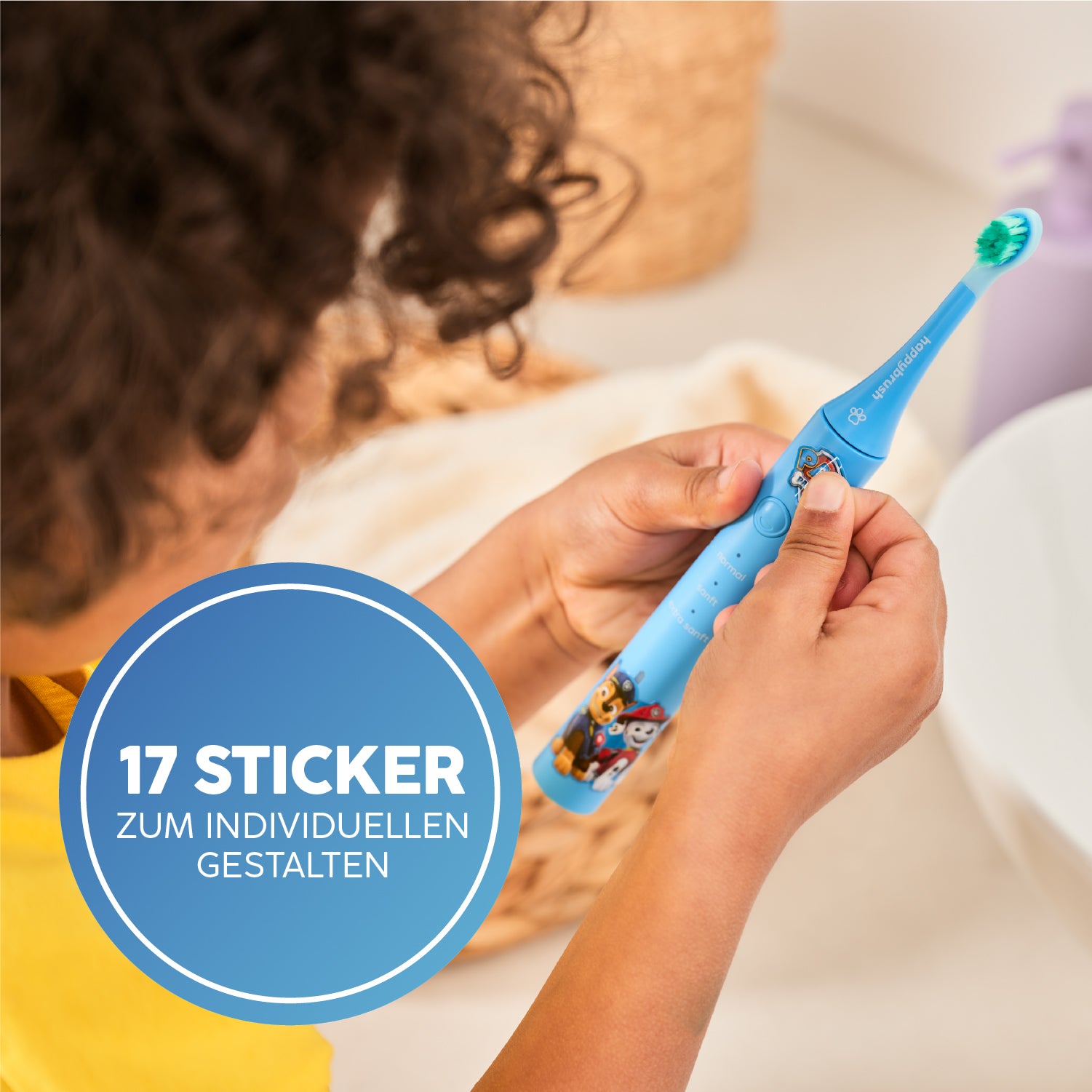 Ein Kind hält eine Happybrush Kinderzahnbürste mit blauer Farbe und Aufklebern.